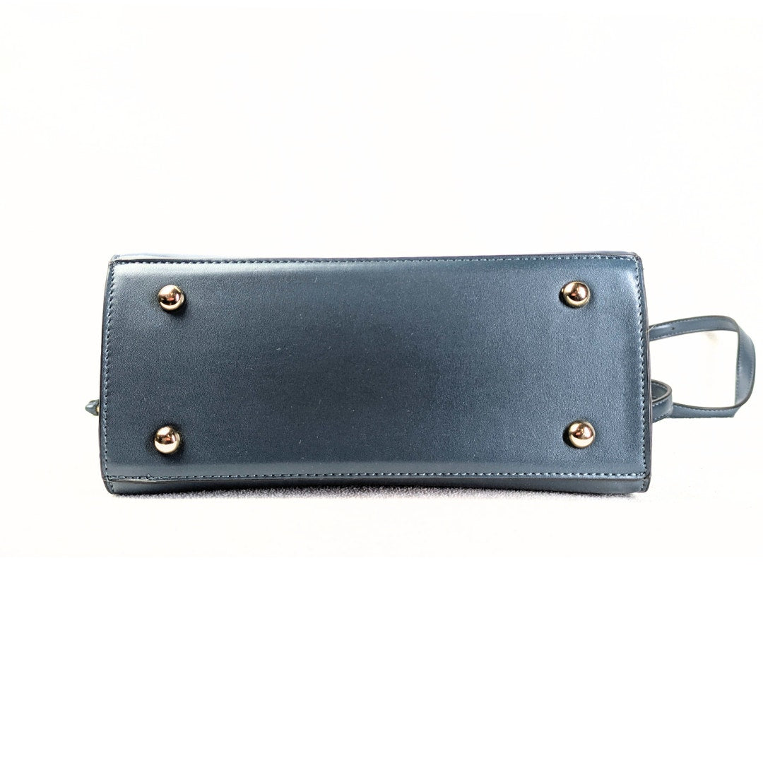 The bottom of the Dune London Purce Convertible Crossbody Satchel Handbag With a Wallet photographed on the white background.