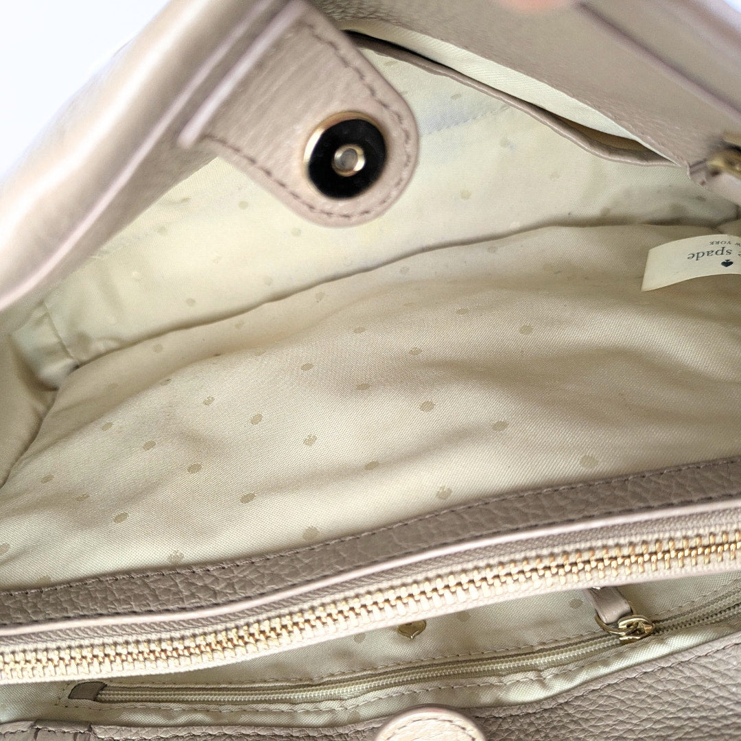 Close-up of a light-colored handbag with a visible brand tag.