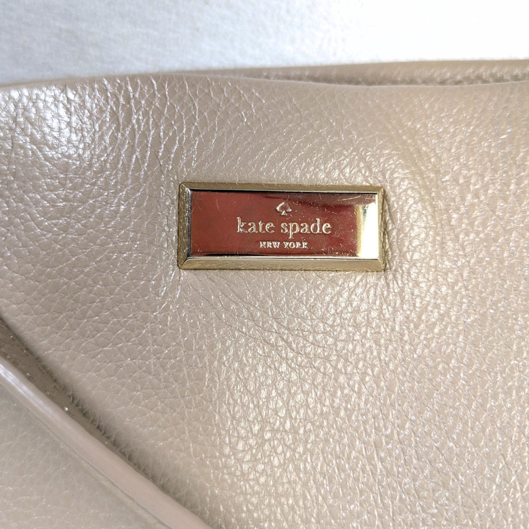 Beige handbag with a 'kate spade New York' label on a white background