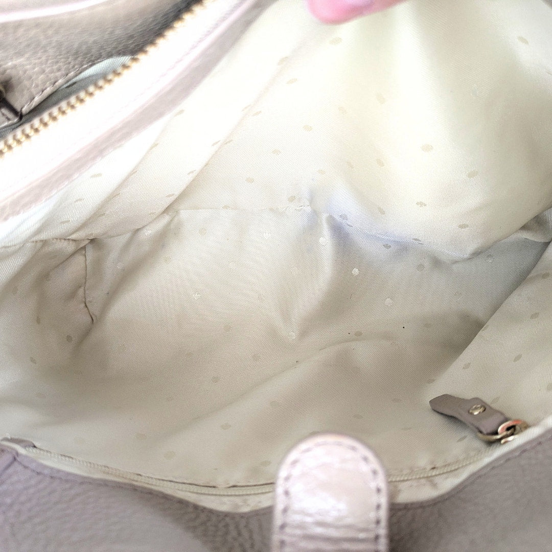 Close-up of a beige handbag with visible satain on the interior lining.
