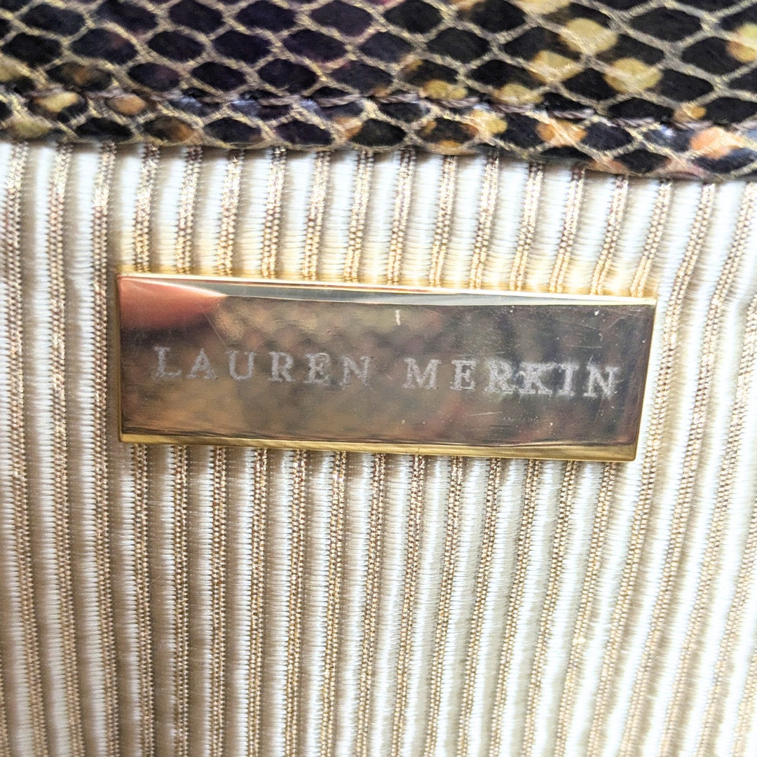 The metal plague inside of the Lauren Merkin Python Skin Pattern Faux Leather Clutch.