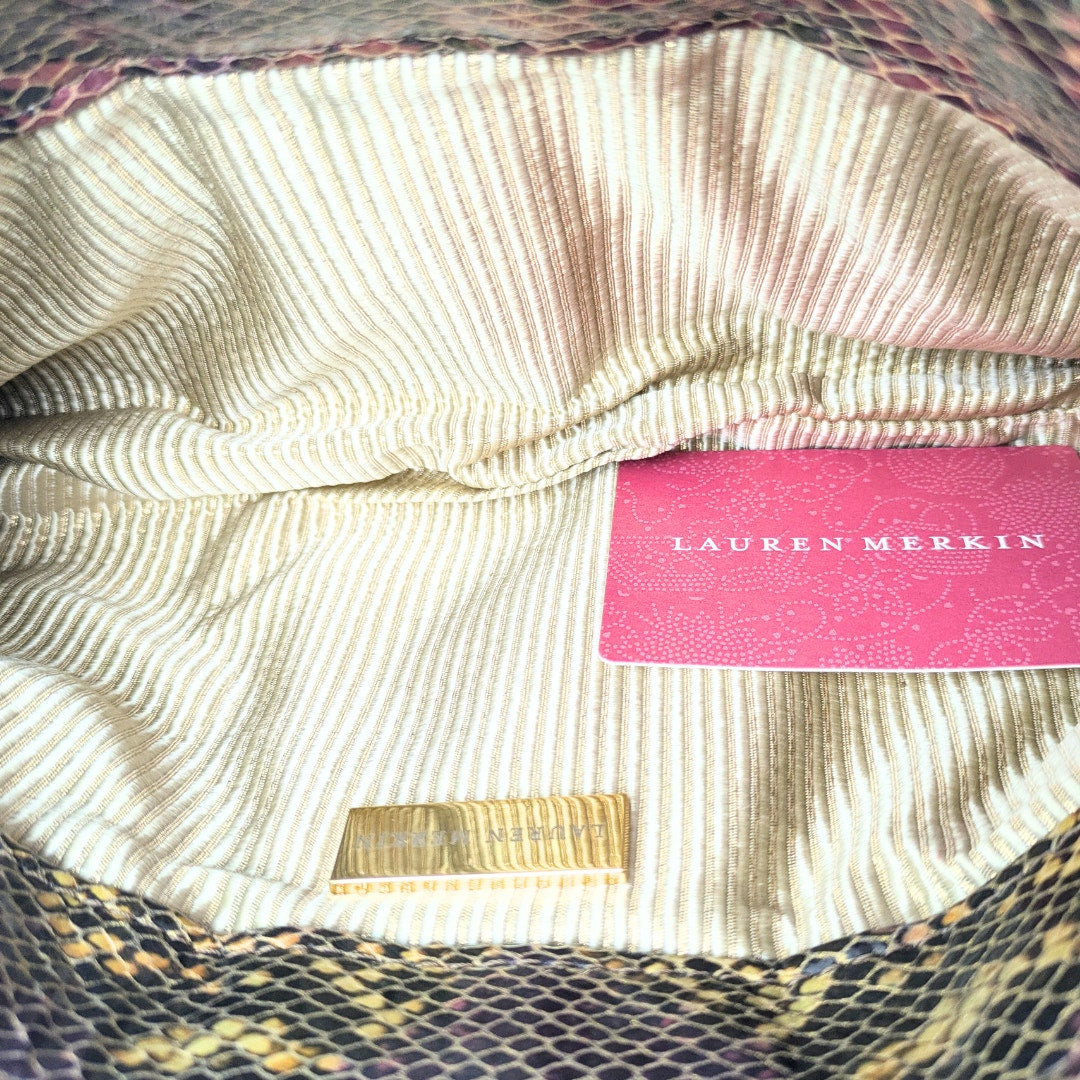 Close-up of a textured fabric surface with a pink label and gold tag, featuring the brand 'Lauren Merkin'.