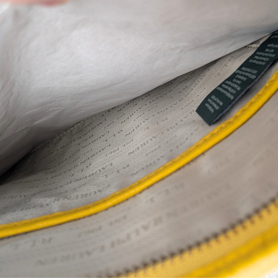 Close-up of a textured gray fabric with a yellow zipper and green label.