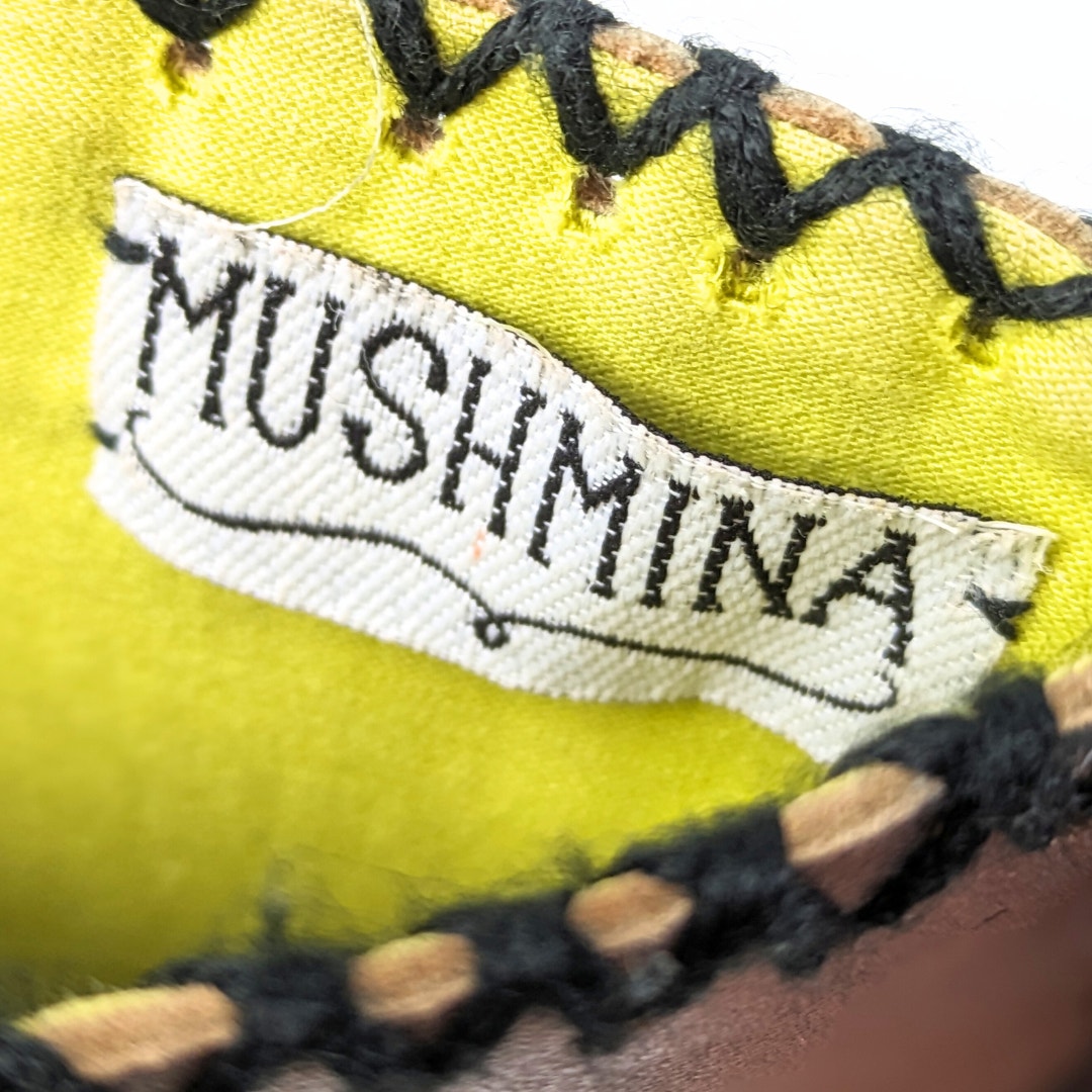 The close-up view of the logo patch inside MUSHMINA Metallic Gold Faux Leather Crossbody Bag.