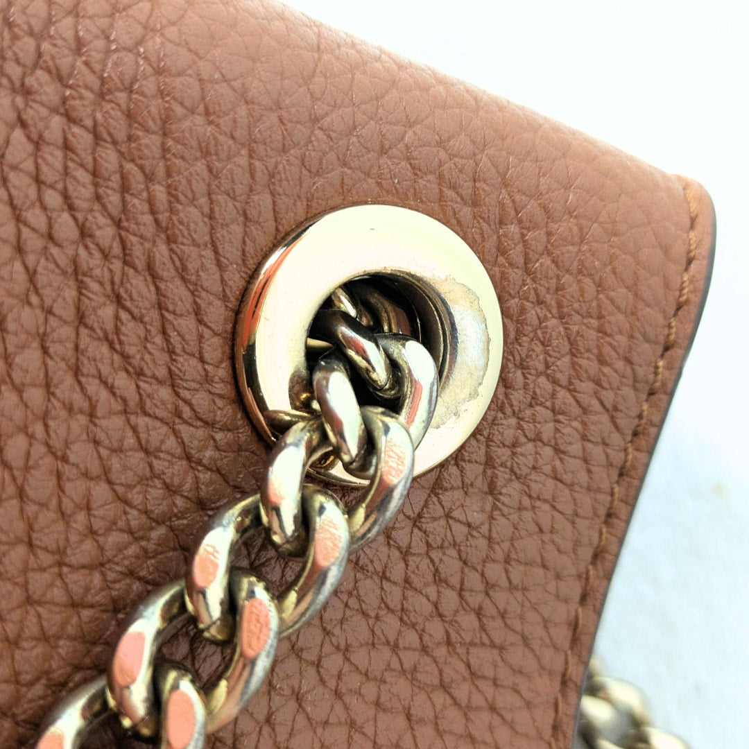 The close up of the scratched handbag hardware.