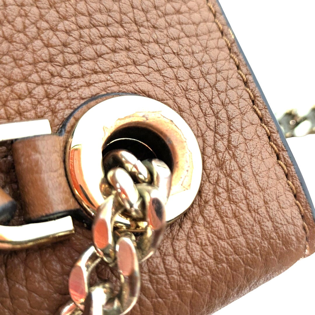 The worn down hardware of the handbag .