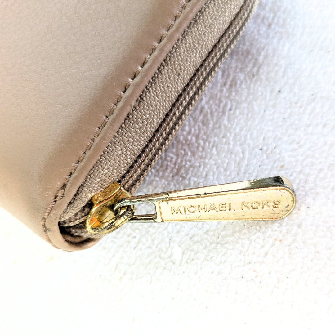The view of the scratched hardware parts of the zipper belogning to the Michael Kors Saratoga Zip Around Continental Wallet, captured on the white background.