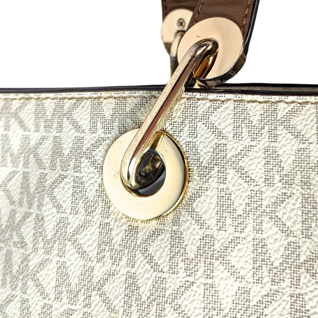 The gold-tone hardware of the Michael Kors Signature Raven Large North South Top Zip Tote.