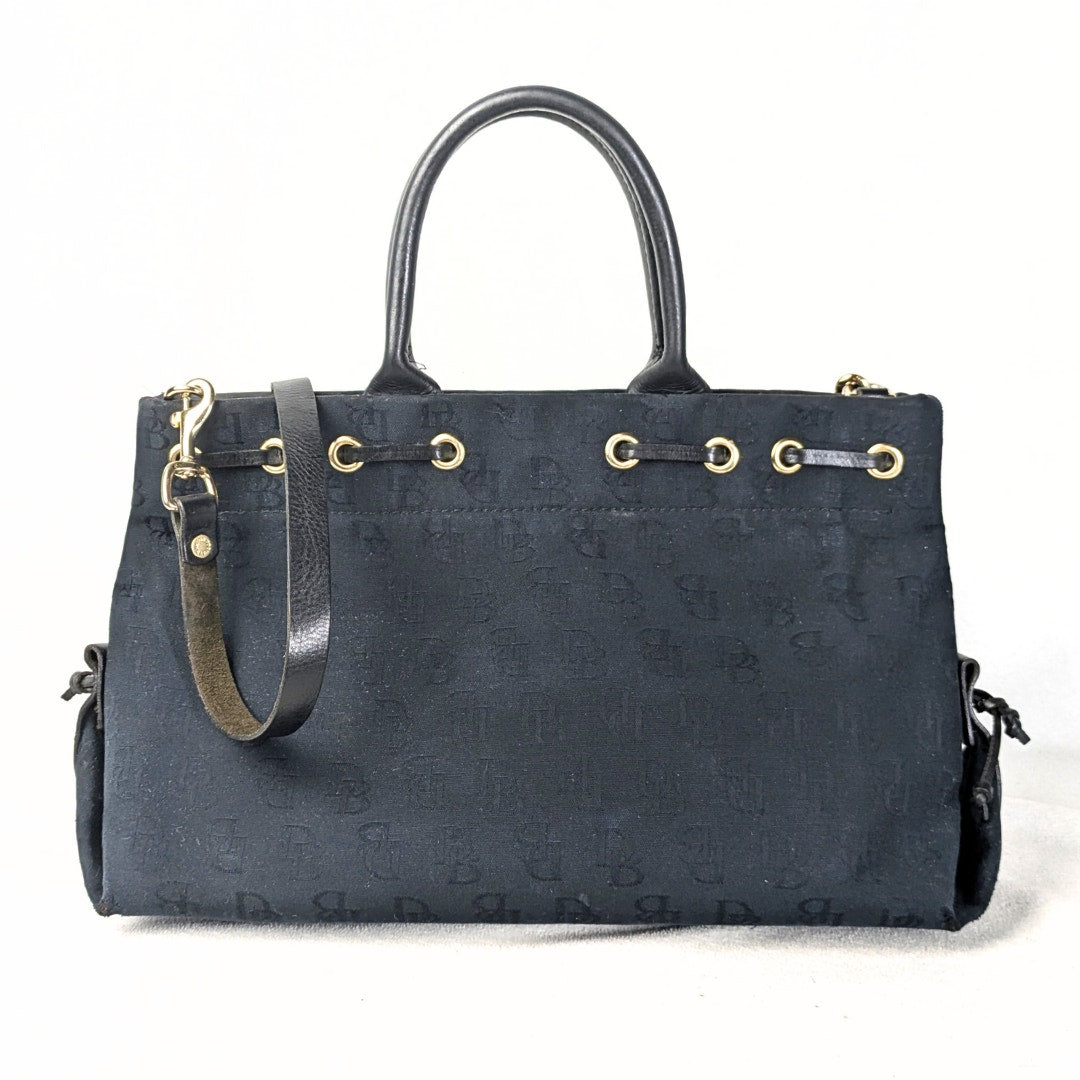 Pre-loved Dooney & Bourke Monogram Canvas Satchel with Tassel in Black photographed from the back side.