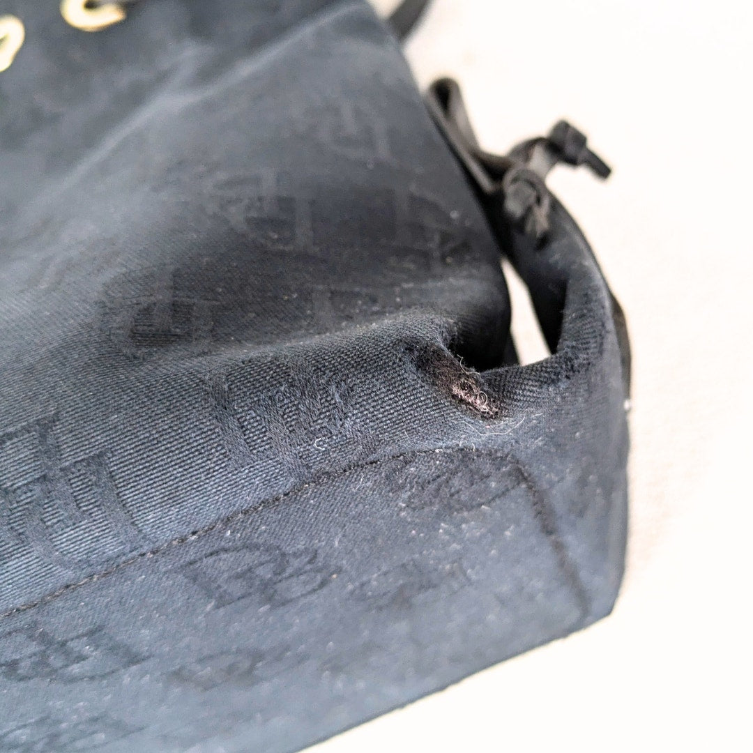 Bottom left corner of the pre-loved Dooney & Bourke Monogram Canvas Satchel with Tassel in Black.