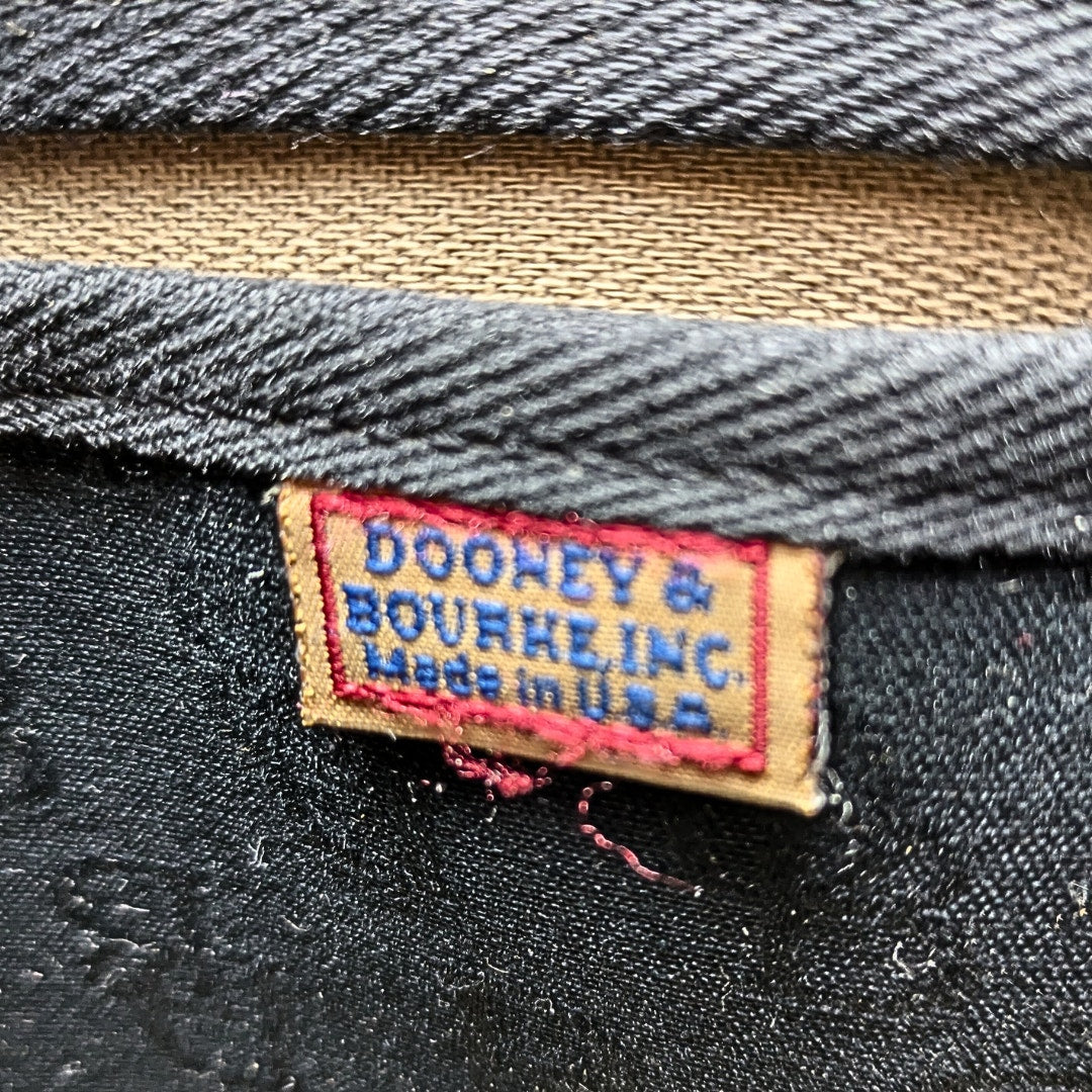 Signature label of the pre-loved Dooney & Bourke Monogram Canvas Satchel with Tassel in Black.