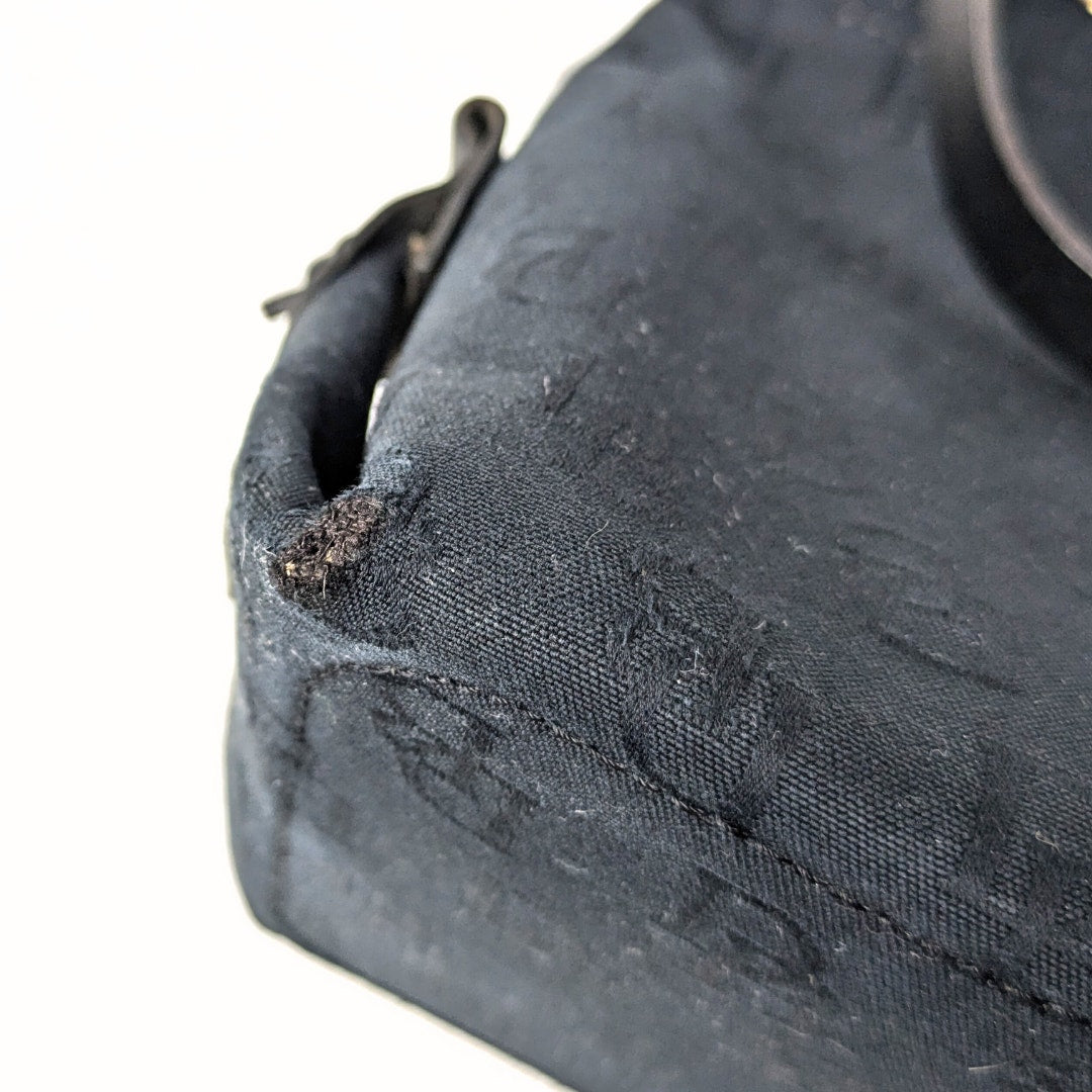 Bottom left corner of the pre-loved Dooney & Bourke Monogram Canvas Satchel with Tassel in Black.