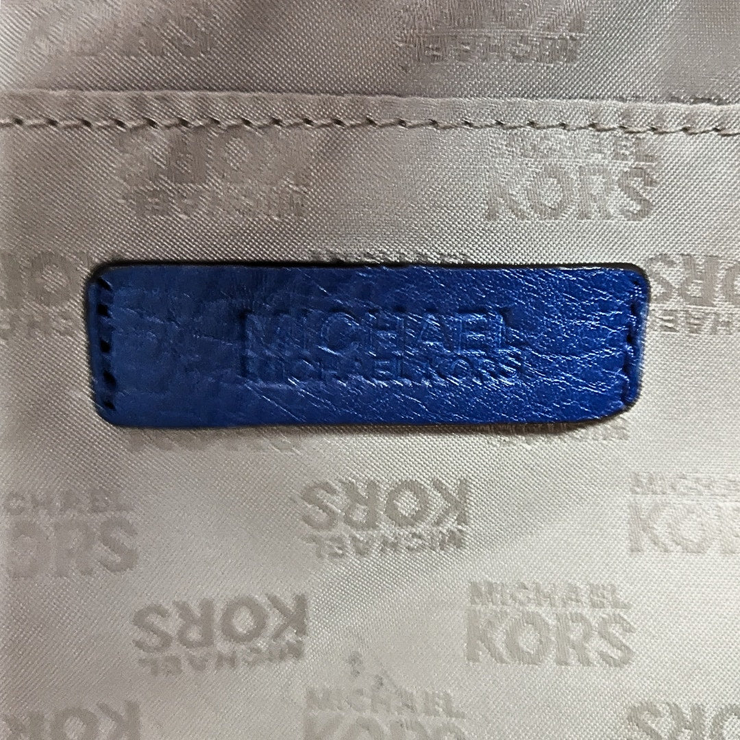 Interior patch of the pre-owned Michael Kors Jet Set East West Chain Tote Bag in Blue photographed from the side.
