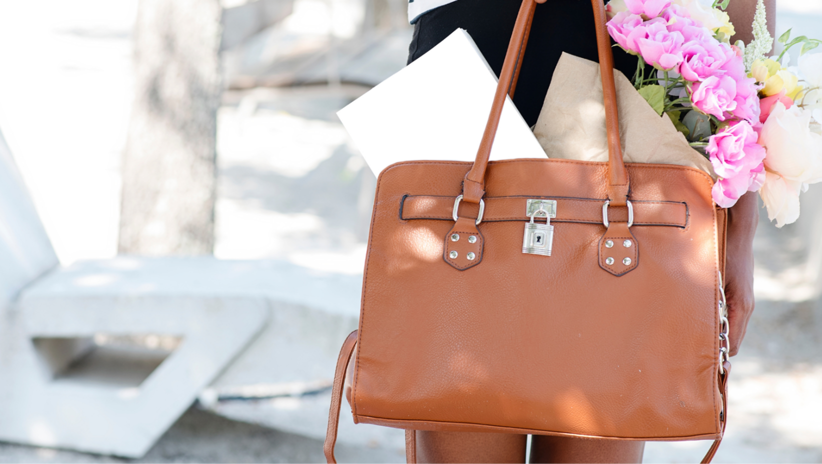 Brown leather handbag held by a person with a blurred background
