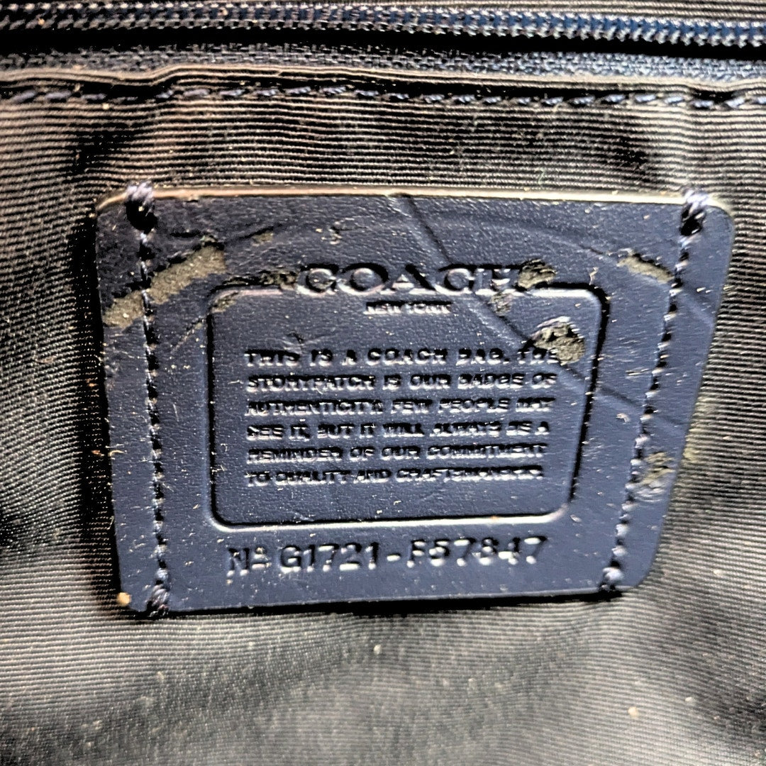 Close-up of a Coach bag label on black leather.