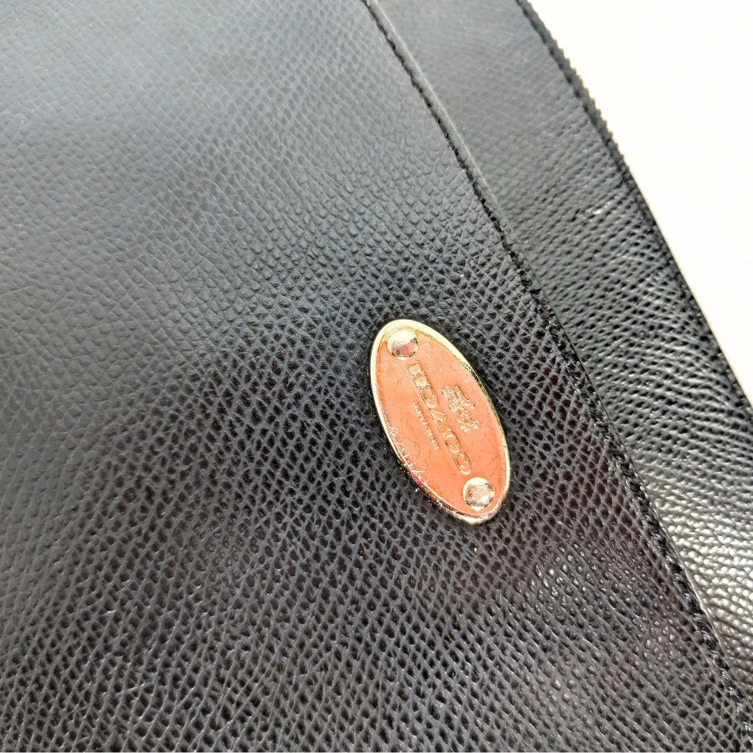 The close-up on the scratched exterior metal logo plaque on the COACH Polly Crossgrain Leather Crossbody Bag. 