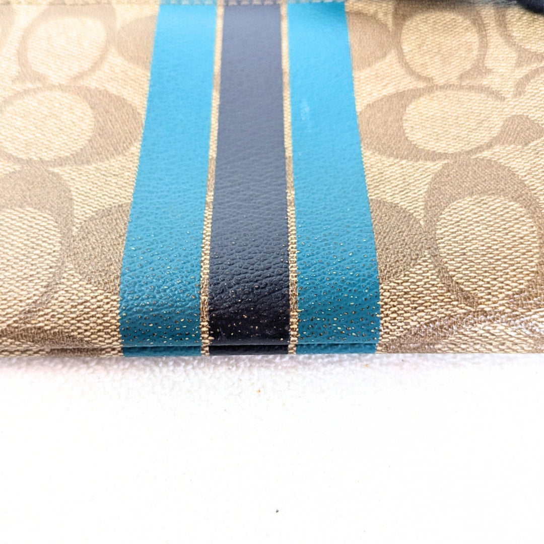 The close-up view of the worn down part of the external print on the COACH Signature Canvas Stripe Wallet Pouch. 
