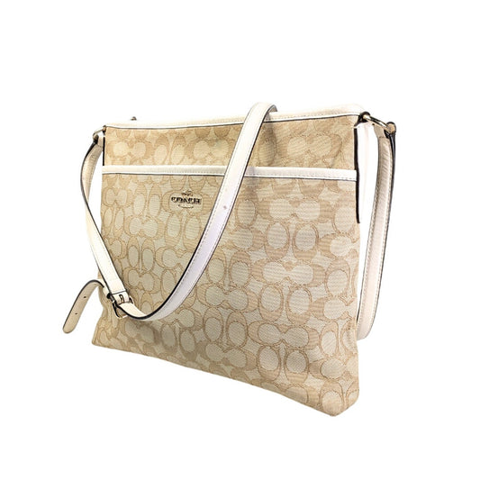A pre-owned COACH Signature Jacquard Crossbody Bag with a beige jacquard design, white leather finishes, and gold-tone hardware. The bag has an adjustable strap, a front slide pocket, and a brown canvas lining.