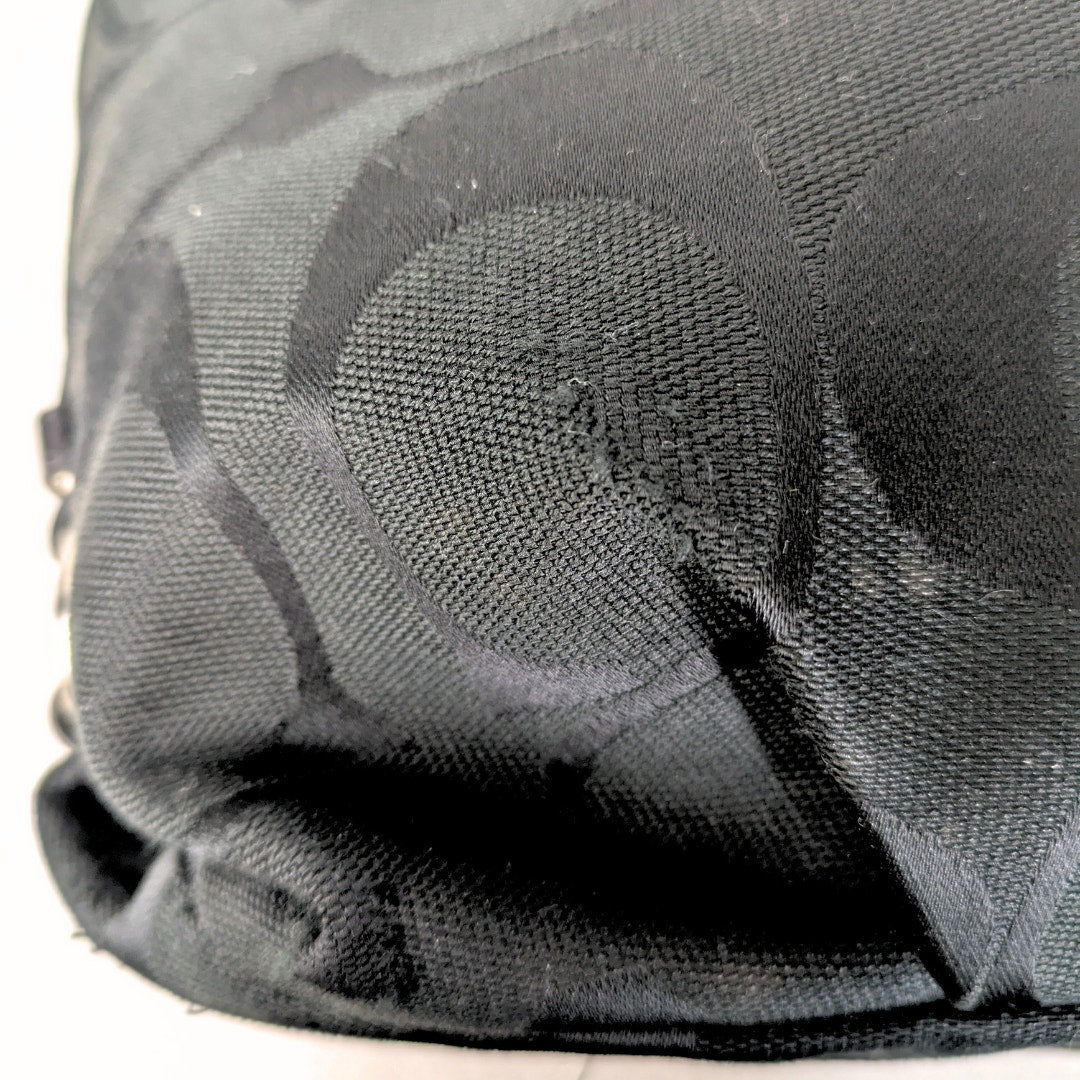 The close-up on a bottom corner of the Coach Monogram Hobo Shoulder Bag. 