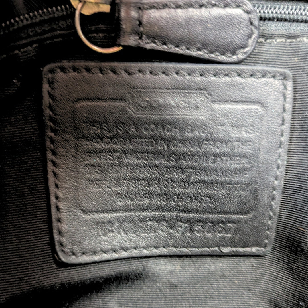 The close-up on a leather embossed creed inside the Coach Monogram Hobo Shoulder Bag.