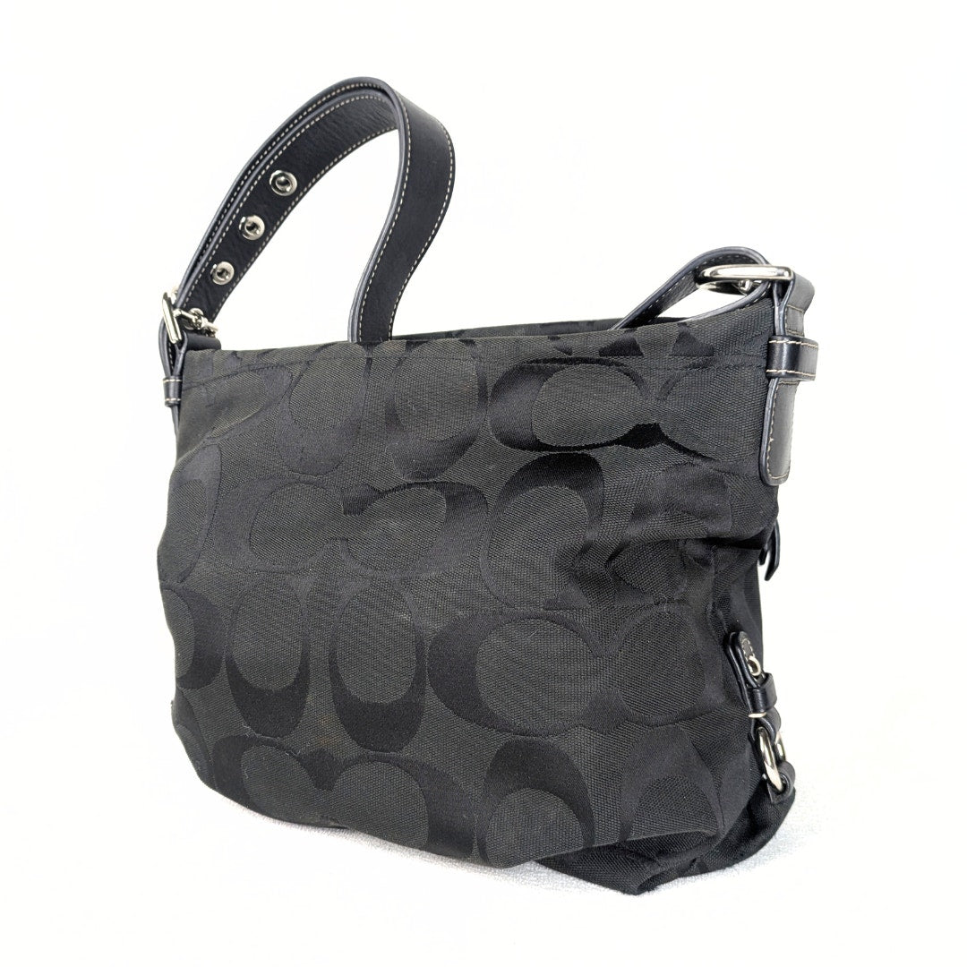 A black Coach Monogram Hobo Shoulder Bag with a jacquard body, leather shoulder strap, and silver-tone hardware.