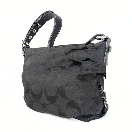 A black Coach Monogram Hobo Shoulder Bag with a jacquard body, leather shoulder strap, and silver-tone hardware.