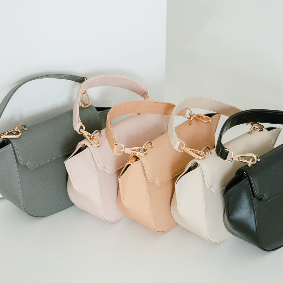 Shoulder bags in various natural colors shades lined up one next to the other.