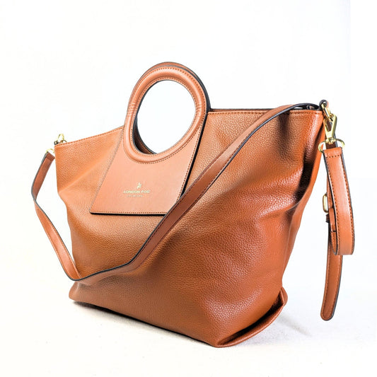 A brown faux leather handbag with two round handles and an adjustable shoulder strap, featuring gold-tone hardware.