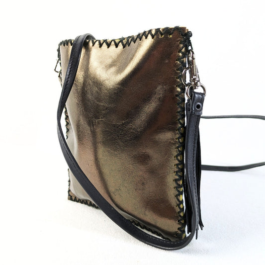 A metallic gold faux leather crossbody bag with a black leather strap and a black zipper, featuring a yellow canvas interior and a decorative tassel.