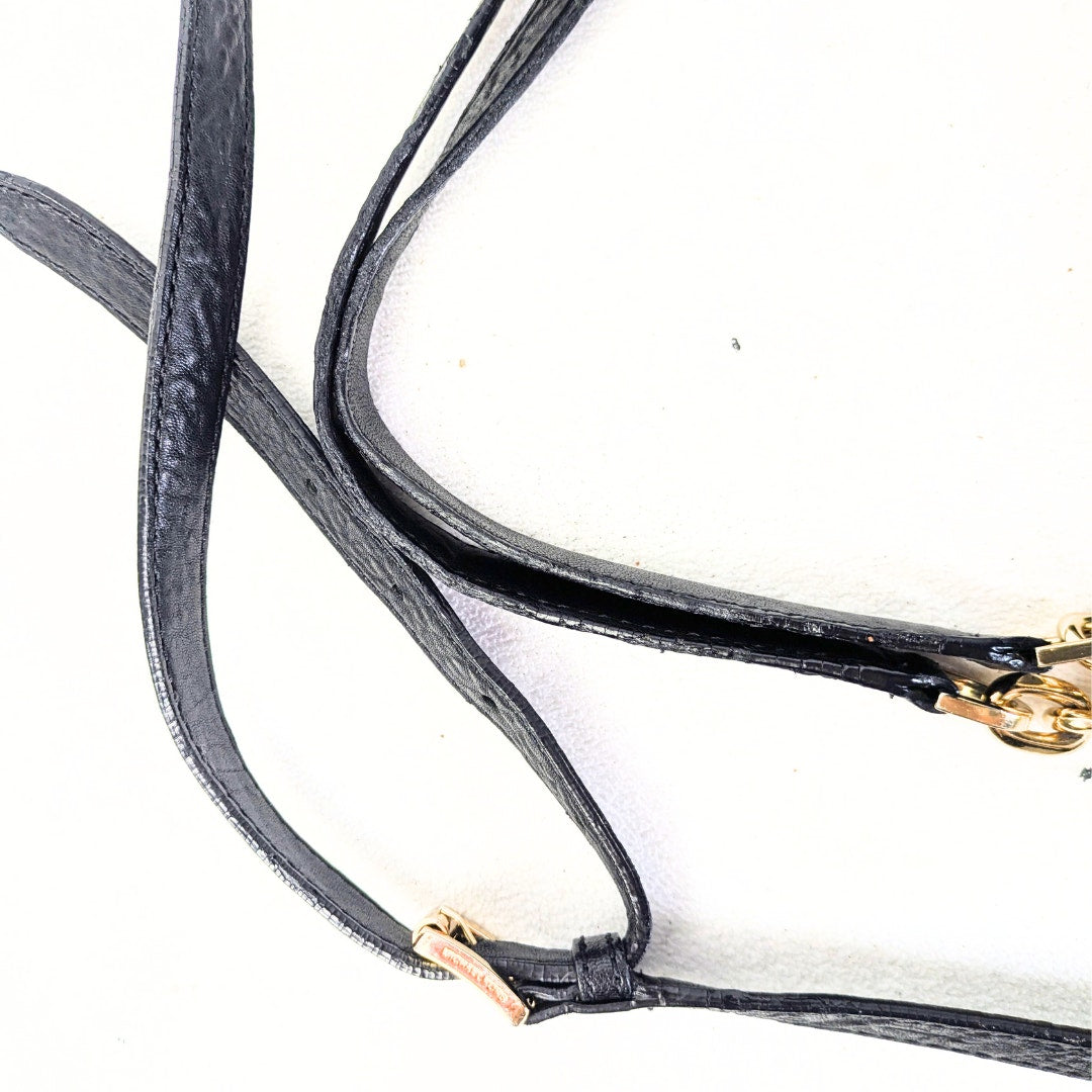 Close-up of a black leather strap with gold hardware on a white background