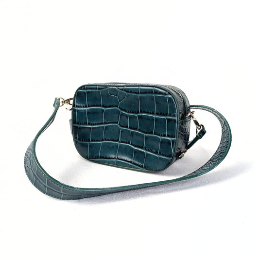 A crocodile embossed leather crossbody bag with a green exterior, gold-tone hardware, and a pink canvas lining.