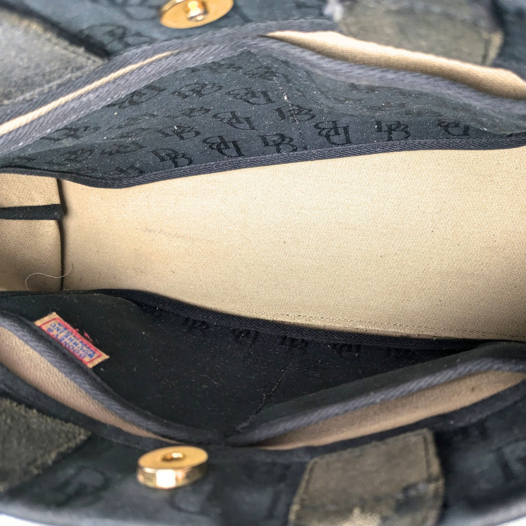 Interior of the pre-loved Dooney & Bourke Monogram Canvas Satchel with Tassel in Black photographed from the left side. 
