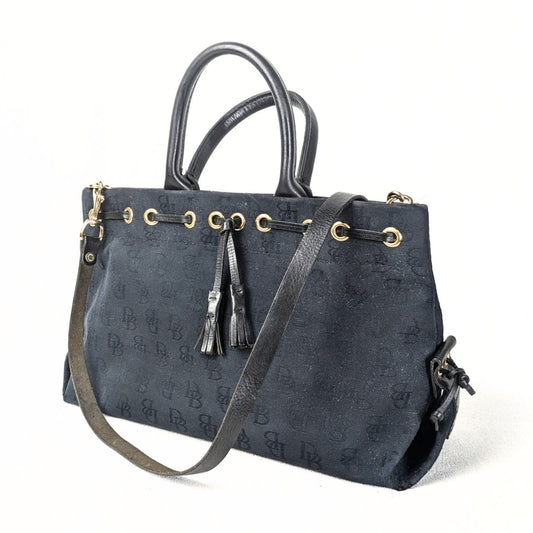 Pre-loved Dooney & Bourke Monogram Canvas Satchel with Tassel in Black photographed from the left side. 