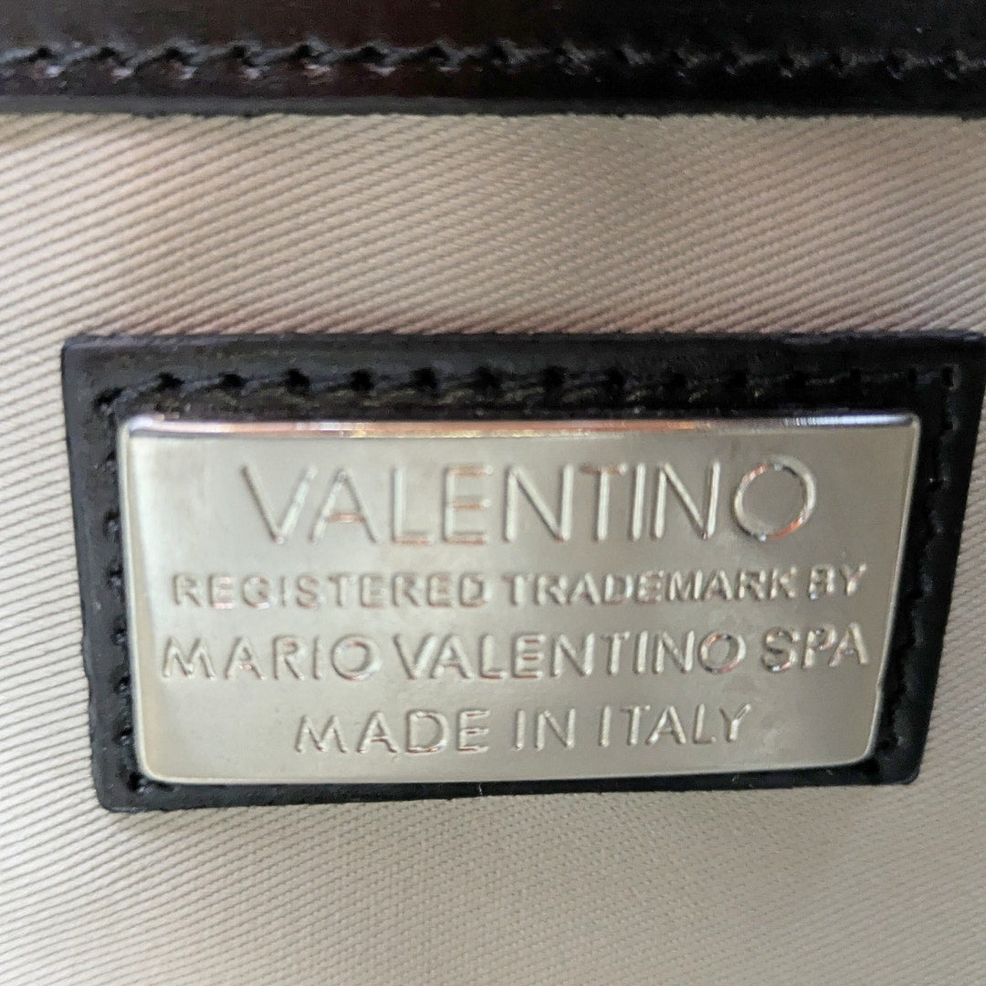 The view of the interior metal brand plaque of Valentino by Mario Valentino Anny Soave Shoulder Bag in Black .